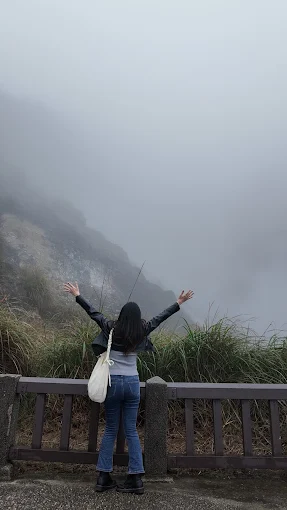 Traveler with arms raised at a misty volcanic viewpoint
