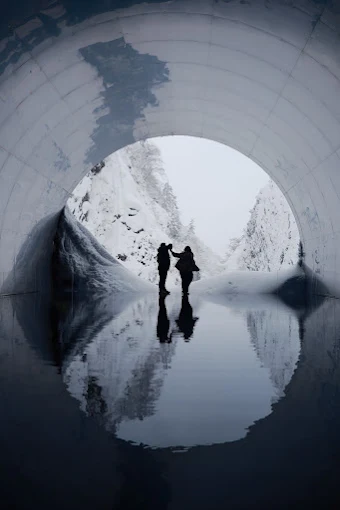 Couple silhouetted in a snowy tunnel with a mirror reflection